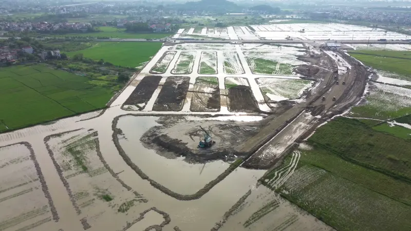 Các ô phố và nền đường nội khu đang san lấp trên cánh đồng, máy xúc làm việc ở góc công trường