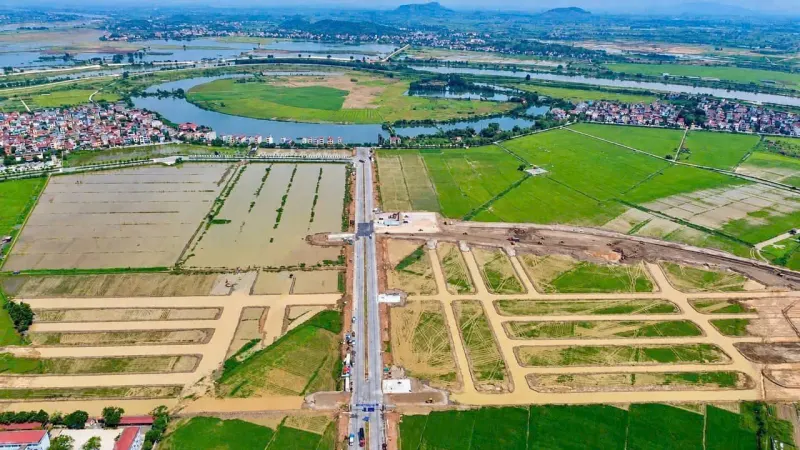 Tuyến đường mới dẫn thẳng vào công trường, hai bên đã vạch ô lô đất, phía xa là khúc sông quanh bán đảo Hòa Long